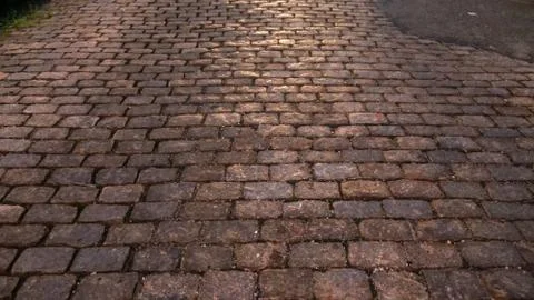 Horizontal image of a cobblestone street back lit by car headlights Stock Photos