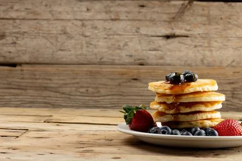 Horizontal image of stack of pancakes with blueberries and maple syrup, on wood Stock Photos