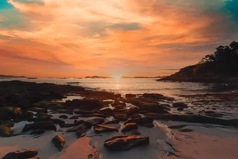 Horizontal image of a tide on the beach over the sand during a colorful sun.. Photos