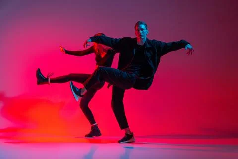 Horizontal image of young couple dancing hip-hop isolated over gradient Fotos Stock