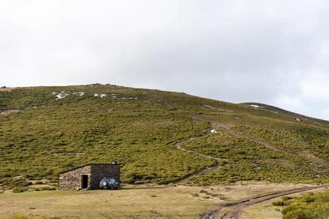 Horizontal landscape view of a mountain side with a shelter and an off-road c Stock Photos