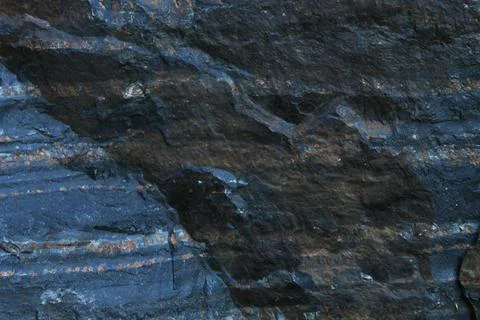 Horizontal layered dark slate rock texture with rusty mineral streaks Stock Photos