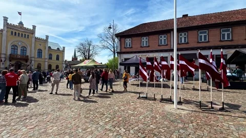 Horizontal Pan Of Crowd And Latvia Flags In Kuldiga Town Square During Sunny Day Stock Footage 334693704