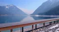 Horizontal pan of wooden pier near beautiful lake, mountains covered with snow 4k or 4k+ Resolution