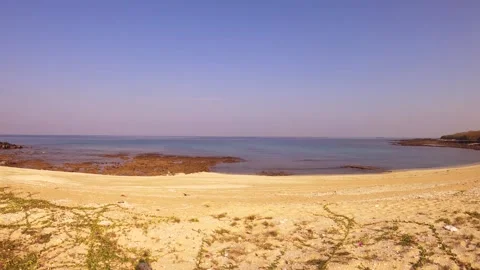 Horizontal pane view from sandy beach side and dry bush grassy hill with turquoi Stock Footage 240483226