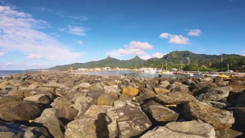 Horizontal pane view of sandy rocky bay area in Avatiu Harbor look out to boats  Stock-Footage 258443485
