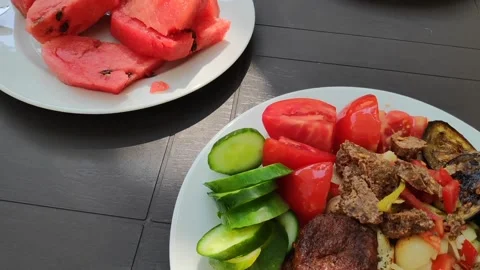 Horizontal panning across table with plates of meat vegetables and watermelon Stock Footage 345213762