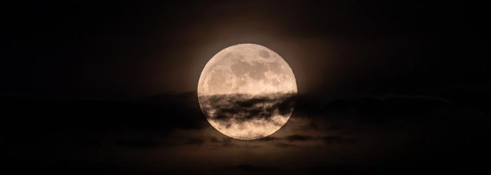 Horizontal panoramic image of the full moon slightly obscured by clouds durin Stock Photos