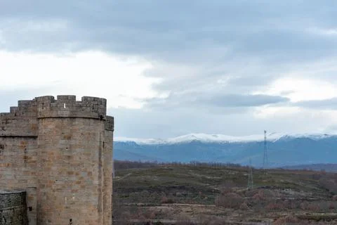Horizontal panoramic view of a stone castle tower and snow-capped mountains i Stock Photos