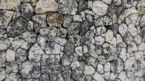 A horizontal perspective captures a rustic dry stone wall built from dark w.. Stock Photos