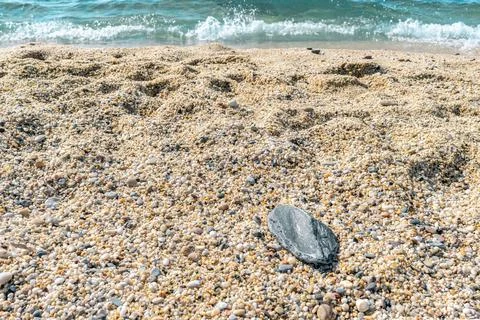 Horizontal perspective of a lonely grey stone on a pebble beach Stock Photos