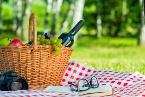 Horizontal photo - picnic objects, fruit basket and wine on the lawn Stock Photos