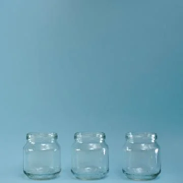 Horizontal row of three transparent jars in a blue square. Stock Photos