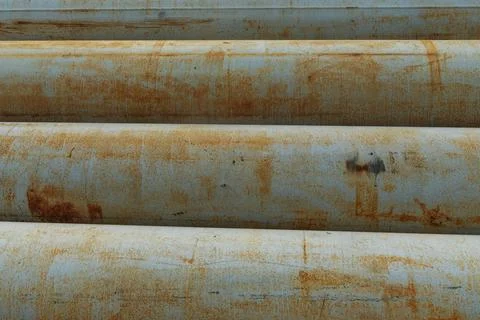Horizontal rusty metal pipes lying in a row close up. Heavy metal construct.. Stock Photos