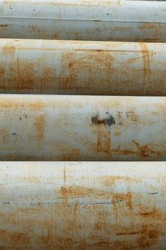 Horizontal rusty metal pipes lying in a row close up. Heavy metal construct.. Stock Photos