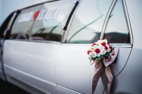 Horizontal shot of a cute tiny bouquet on a door of a beautiful white limousi Foto stock
