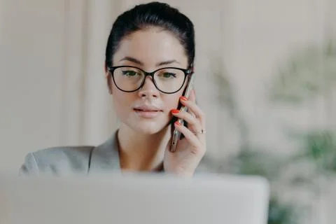 Horizontal shot of dark haired experienced woman with serious expression, mak Stock Photos