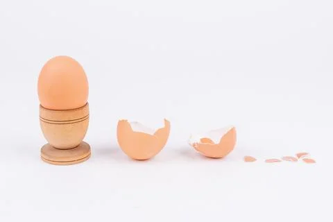 Horizontal shot hen egg in old wooden egg stand and multiple broken egg shells Stock Photos