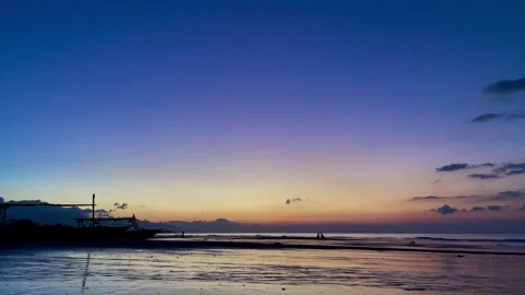 Horizontal shot of peaceful beach dawn with boat silhouette in Bali Stock Footage 343796773
