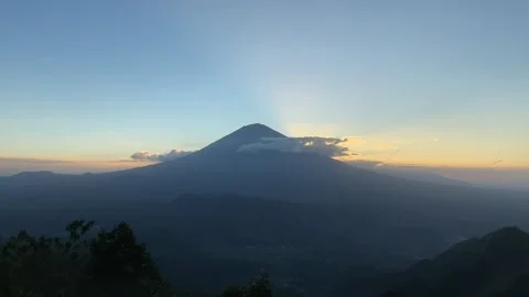 Horizontal Shot of Sunbeams Bursting Behind Mount Agung Silhouette Video stock 341552173
