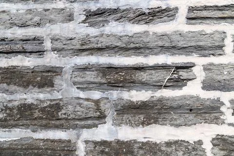 Horizontal stone wall with visible strata and repaired mortar lines Stock Photos