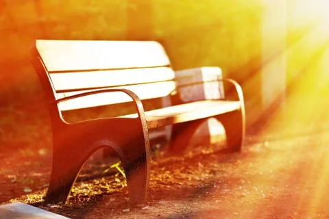 Horizontal sunset park bench in light rays background Stock Photos