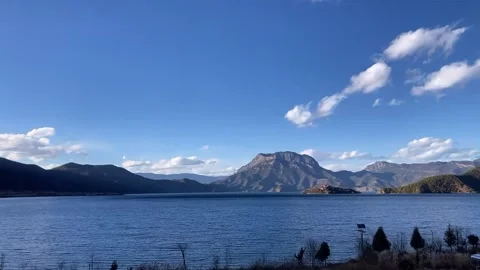 Horizontal Timelapse of Clouds Moving Fast over Blue Alpine Lake and Mountai Video stock 326083935