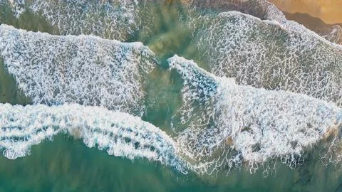 Horizontal top down aerial view of rolling turquoise sea waves with white f.. Stock Photos
