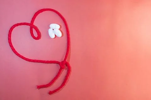 Horizontal top view of red string in the shape of a heart with white tablets Stock Photos