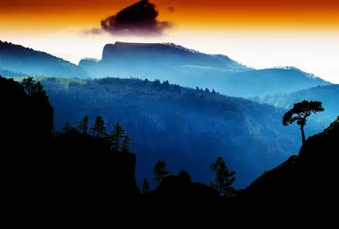 Horizontal vdramatic mountain trees on rocks silhouette sunset b Stock Photos