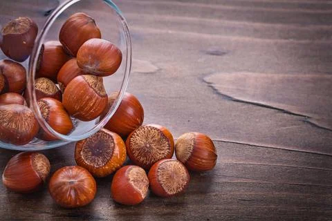 Horizontal version Stack of hazelnuts in glass bowl on vintage wooden board Foto stock