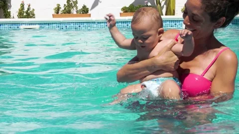 Horizontal video of a mom playing with her baby in the pool for the first tim Stock Footage 220351393