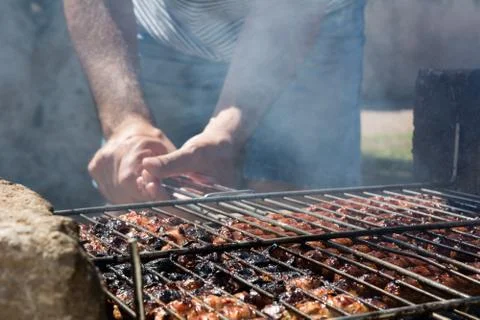 Horizontal View of A Man Holding a Grill Burning on Barbecue Full of Sausage Stock Photos