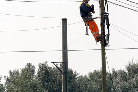 Horizontal View of a Worker Repairing a Light Pole With Safety Tools on Grey Stock Photos