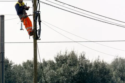 Horizontal View of a Worker Repairing a Light Pole With Safety Tools on Grey Stockfoto's