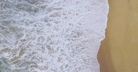 Horizontal wipe of waves breaking on sandy beach aerial drone shot great for  Stock Footage 87573764