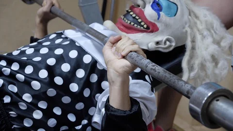 Horrible clown practices bench press with metal bar Stock Footage 112489636