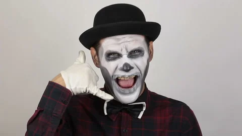 A horrible man in clown makeup makes   asking him to call him back. Stock Footage 140931406