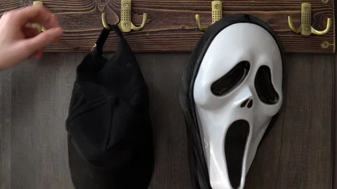 A horrible scream mask hangs on a hook and is taken by a human. A maniac in a Stock Footage 163777410