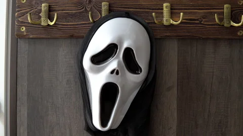 A horrible scream mask hangs on a hook and is taken by a human. A maniac in a Stock Footage 163777521