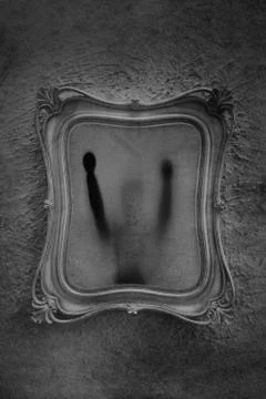 Horror concept of a ghostly doll trapped in an antique picture frame. Stock Photos