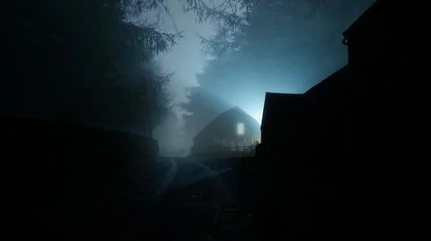 A horror concept of a house with a light in the window. In a spooky forest. Stock Photos