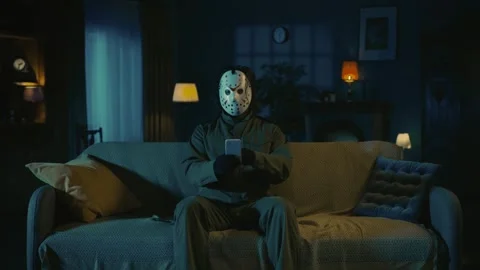 Horror maniac sitting on the sofa in the someones living room and watching Stock Footage 249995426
