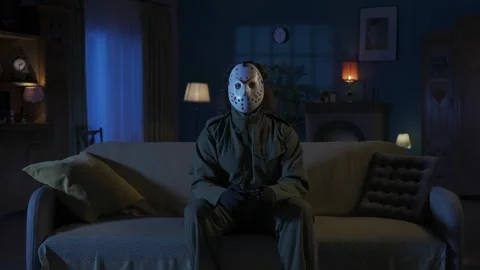 Horror maniac sitting on the sofa in the someones living room and playing video Stock Footage 250006733