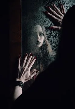 Horror scene: blurry reflection of the ghost girl in old dirty mirror Stock Photos