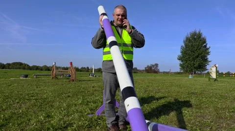 Horse handler talking on smart phone on hurdle field Stock Footage