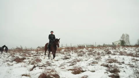 Horse racing across snowfield while rider approaches camera. Energized horse in Video stock 335414601