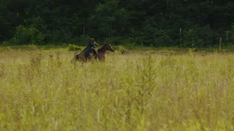 Horseback rider gallops through open field Stock Footage 152182224