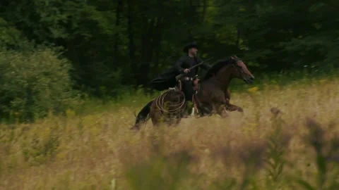 Horseback rider gallops through open field 스톡 동영상 152182299