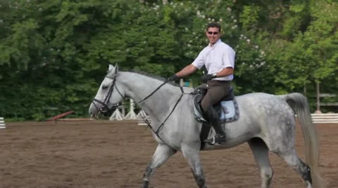 Horseman rides on horseback by equestrian field Stock Footage